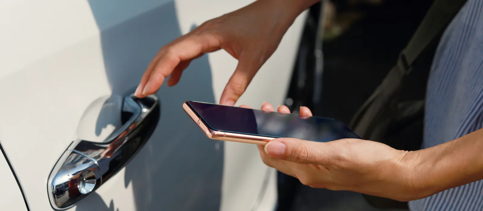 Frau mit Smartphone öffnet eine Autotür mit NFC-Technologie