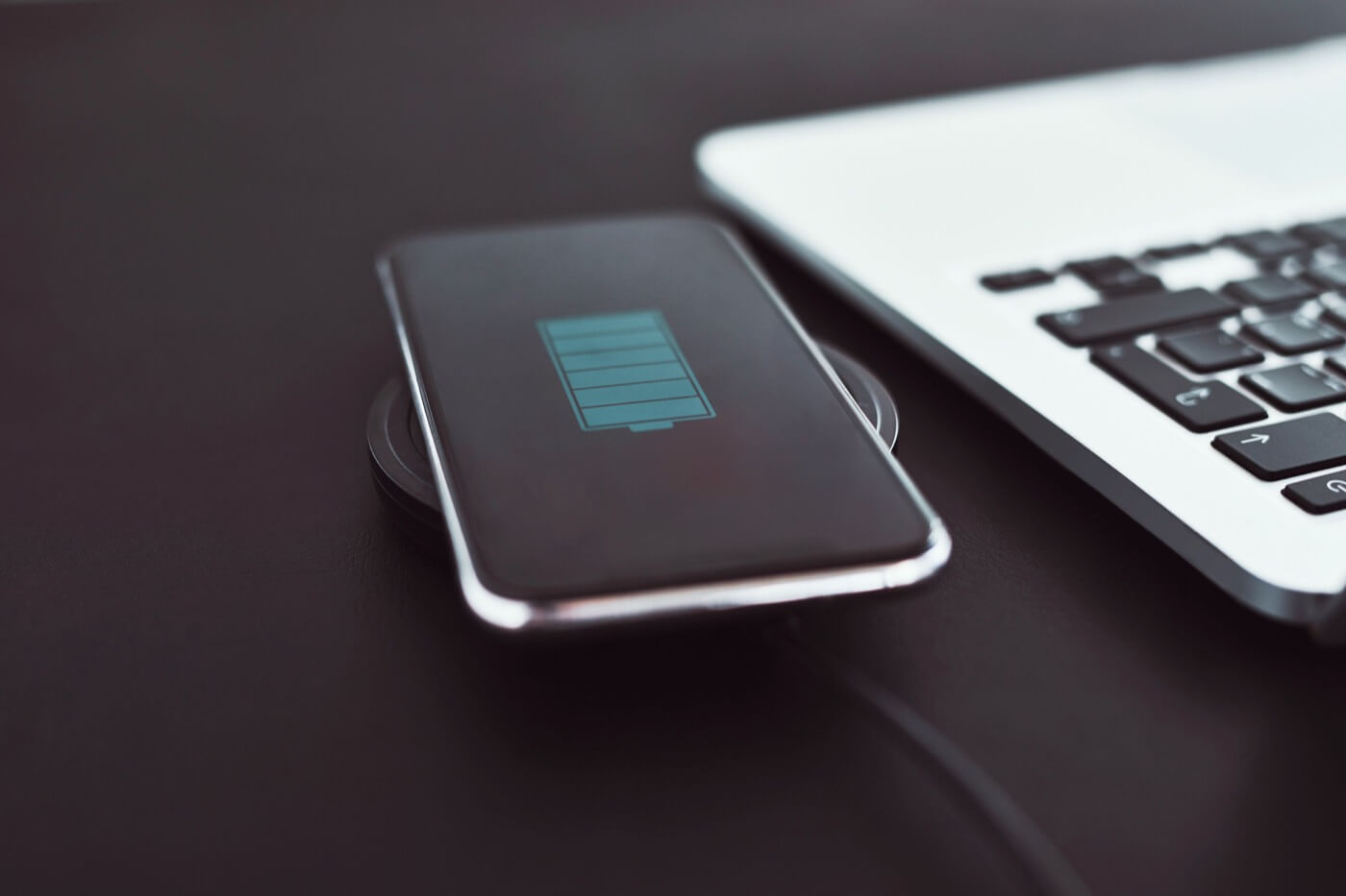 Smartphone on a wireless charger next to a laptop